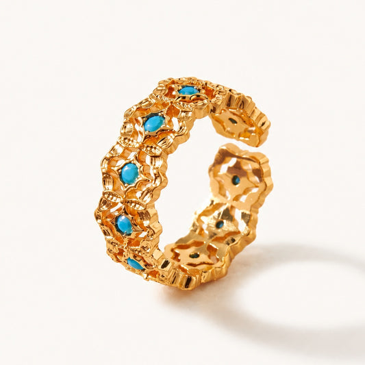 Detailed close-up of a vintage 18K gold-tone adjustable ring featuring intricate filigree, turquoise, and sparkling zircon on a white background.
