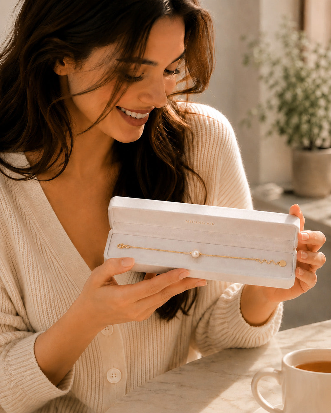Smiling woman opening a white Moonlook jewelry box to reveal a beautiful single pearl necklace.