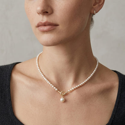 Close up of a woman in a black top wearing an aurora pearl necklace with a twisted gold-tone knot.
