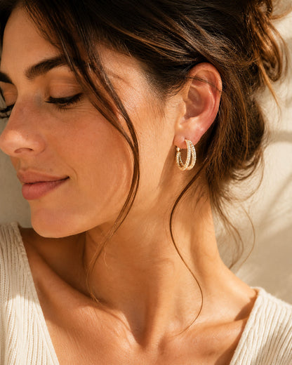 Elegant woman wearing irregular double-layer hoop earrings in gold-tone.