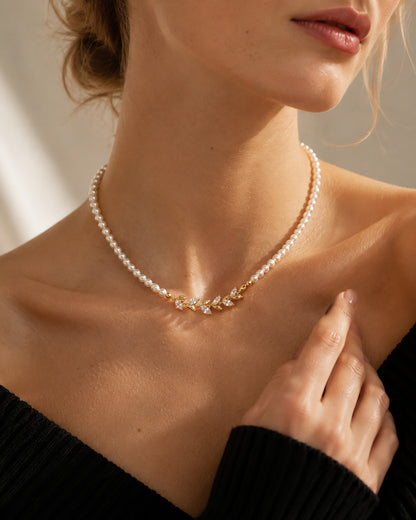 Close-up of an elegant woman wearing a vintage-inspired simulated pearl choker with a sparkling gold-tone zircon leaf centerpiece.